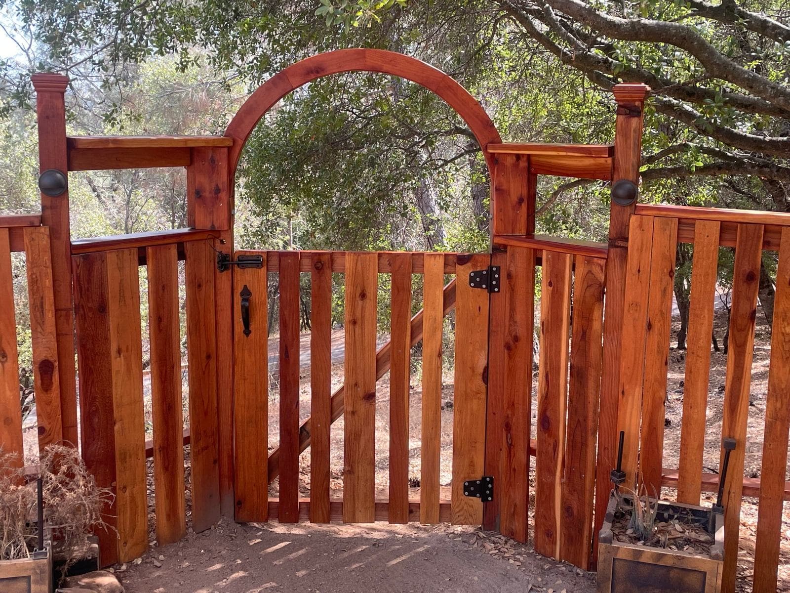 Custom Berco redwood archway gate with forged iron hardware and integrated low-voltage lighting